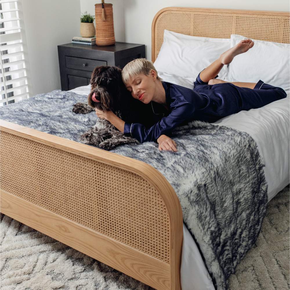 A woman is lying on a bed with a dog, both resting on the Paw PupProtector™ Waterproof Bed Runner - Ultra Plush Arctic Fox Cew Proof Dog Blanket