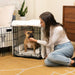 A woman pets a dog sitting inside a black wire crate with a soft white interior, part of the Paw Upgrade Your Dog Crate Kit - Polar White