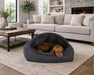 Bowsers Canopy Dog Bed is a dark gray covered bed placed on a living room rug, with a brown dog lying inside under the canopy