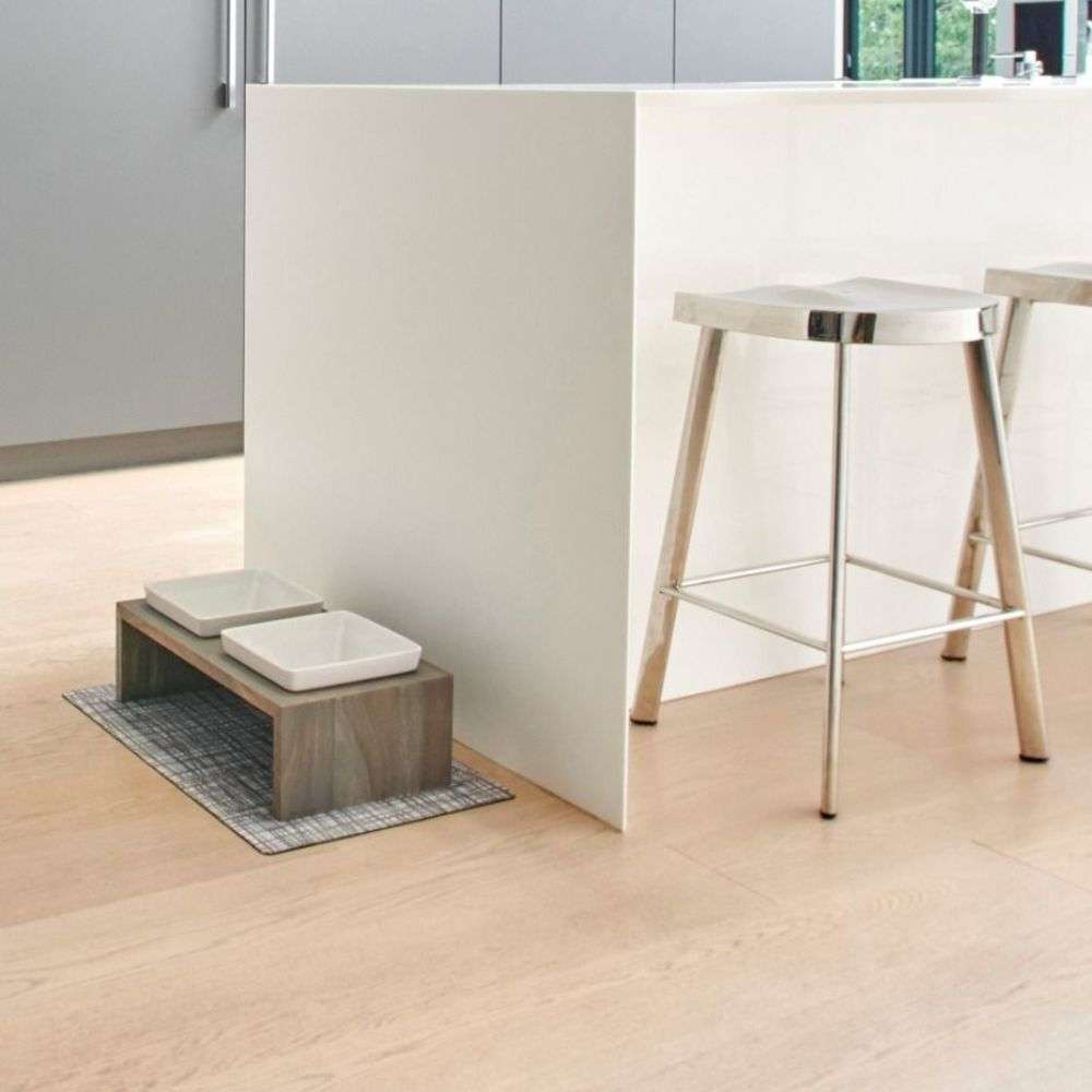 Bowsers Fossil Artisan Wood Feeder Double sits neatly on a floor mat beside a kitchen island with two raised white ceramic bowls