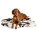 Bowsers Maverick Rugbed shows a brown dog lying relaxed on a cow-patterned mat against a plain background