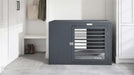 Bowsers Moderno Dog Crate is shown as a dark gray furniture-style crate placed neatly between white cabinets in a bright indoor room