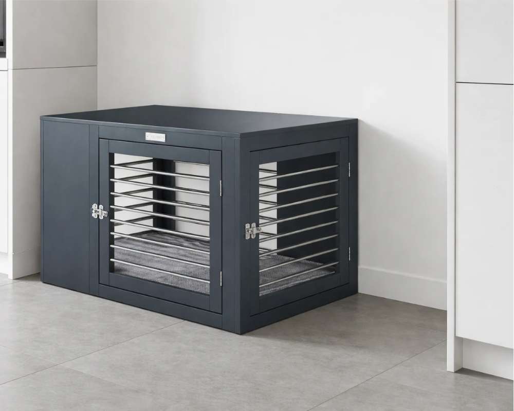 Bowsers Moderno Dog Crate sits in a clean modern room, showing its front and side doors with silver metal bars and a cushioned interior
