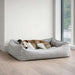 Bowsers One Of A Kind Scoop Dog Bed shows a slender dog lying comfortably in a light gray textured bed near a bright window