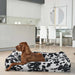 Brown dog rests comfortably inside a black-and-white cow print Bowsers Divine Futon Dog Bed placed in a modern kitchen and dining space