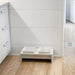 Double Bowsers Fresco Wood Feeder with two white square bowls sits on a wood floor beside a white cabinet and wall
