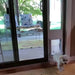 Fluffy white dog using the Security Boss Standard Lockable Patio Pet Door to exit through a window frame