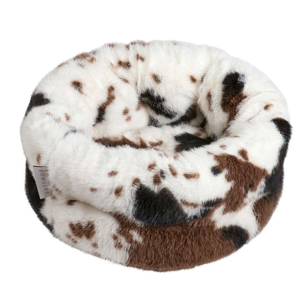 Longhorn Bowsers The Muffy Dog Bed features a white base with brown and black spotted patterns, shaped like a soft, padded nest