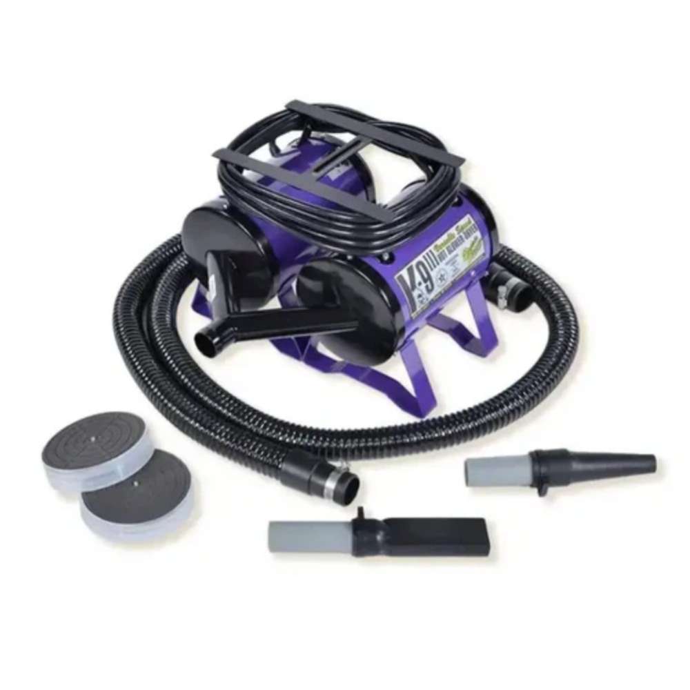 Purple K-9 III Variable Speed Dog Dryer with a coiled hose, attachment nozzles, and filter accessories is shown on a plain white background for professional pet drying