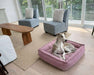 Slender dog lounges inside the berry-colored Bowsers Sterling Lounge Dog Bed in a bright modern living room