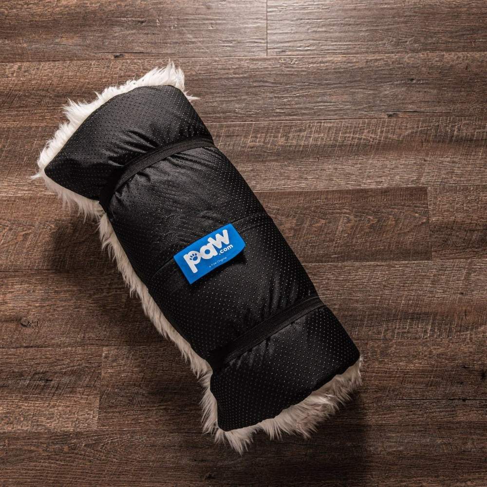 The Grey Paw PupRug™ Portable Orthopedic Dog Bed rolled up and secured with a black cover, placed on a wooden floor