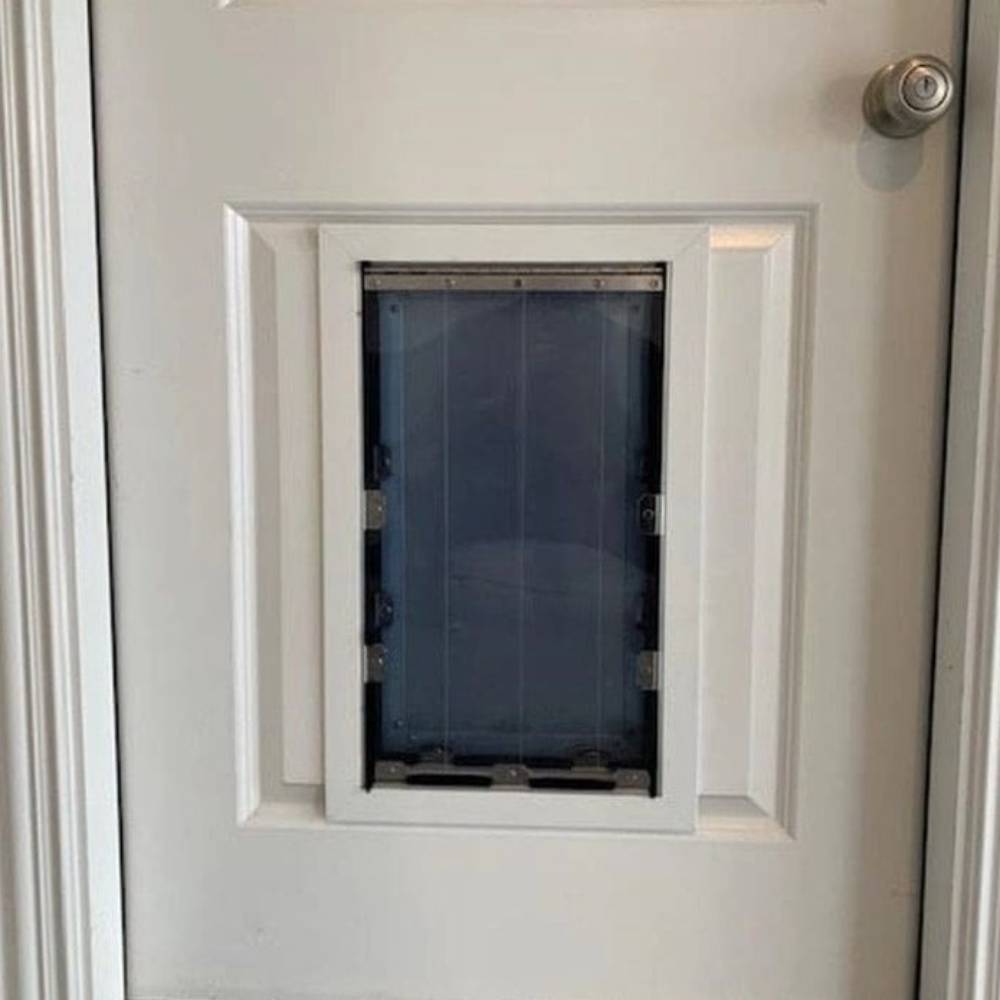 The Security Boss MaxSeal PRO High-Grade Aluminum Dog Door installed on a door, shown with its flap open to demonstrate the easy passage for pets