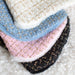 The image depicts a stack of various colored tweed dog coats, showcasing the range of the Hello Doggie Chantel Tweed Dog Coat