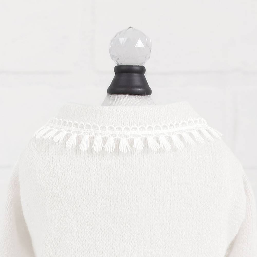 The image depicts the back of a cream-colored sweater featuring a tassel fringe detail around the neckline, described as Hello Doggie Heavenly Kiss Dog Sweater