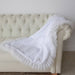The image features the blanket elegantly draped over a sofa, displaying the delicate lace trim and soft, white fabric of the Hello Doggie Romantic Dog Blanket in the Heaven color