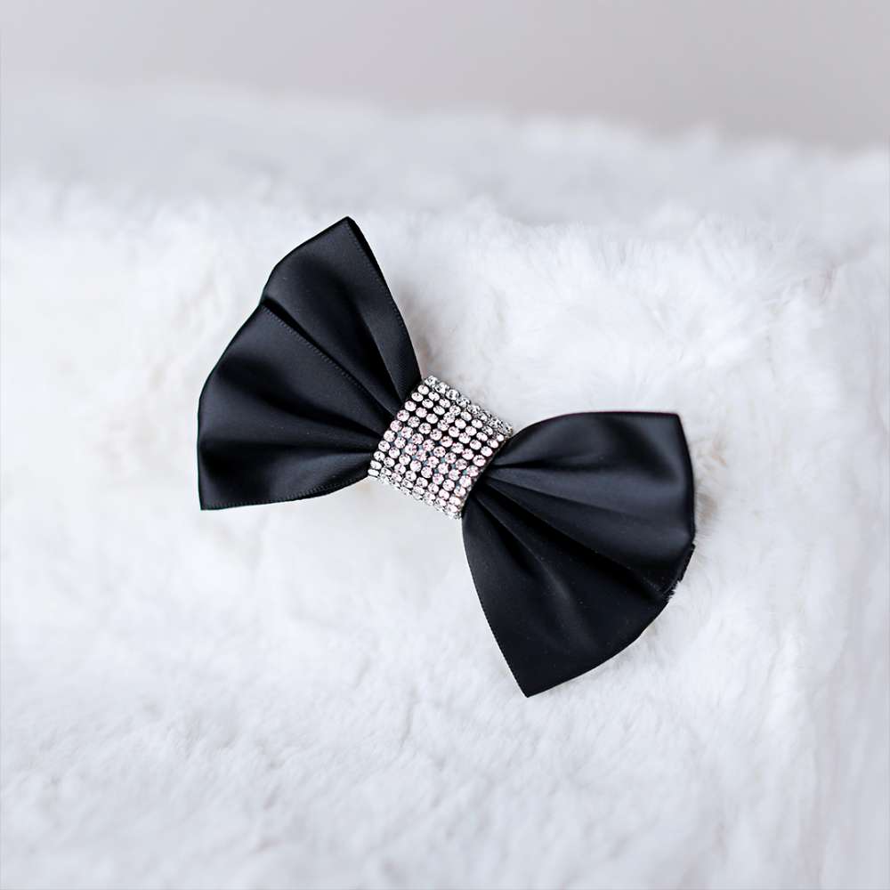 The image is a close-up of a bow decoration on the ivory Hello Doggie Luxury Pet Stairs, featuring a black ribbon and rhinestone center