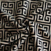 The image is a close-up of the Hello Doggie Obsidian Dog Blanket, highlighting the intricate black and tan Greek key pattern on its soft, plush fabric