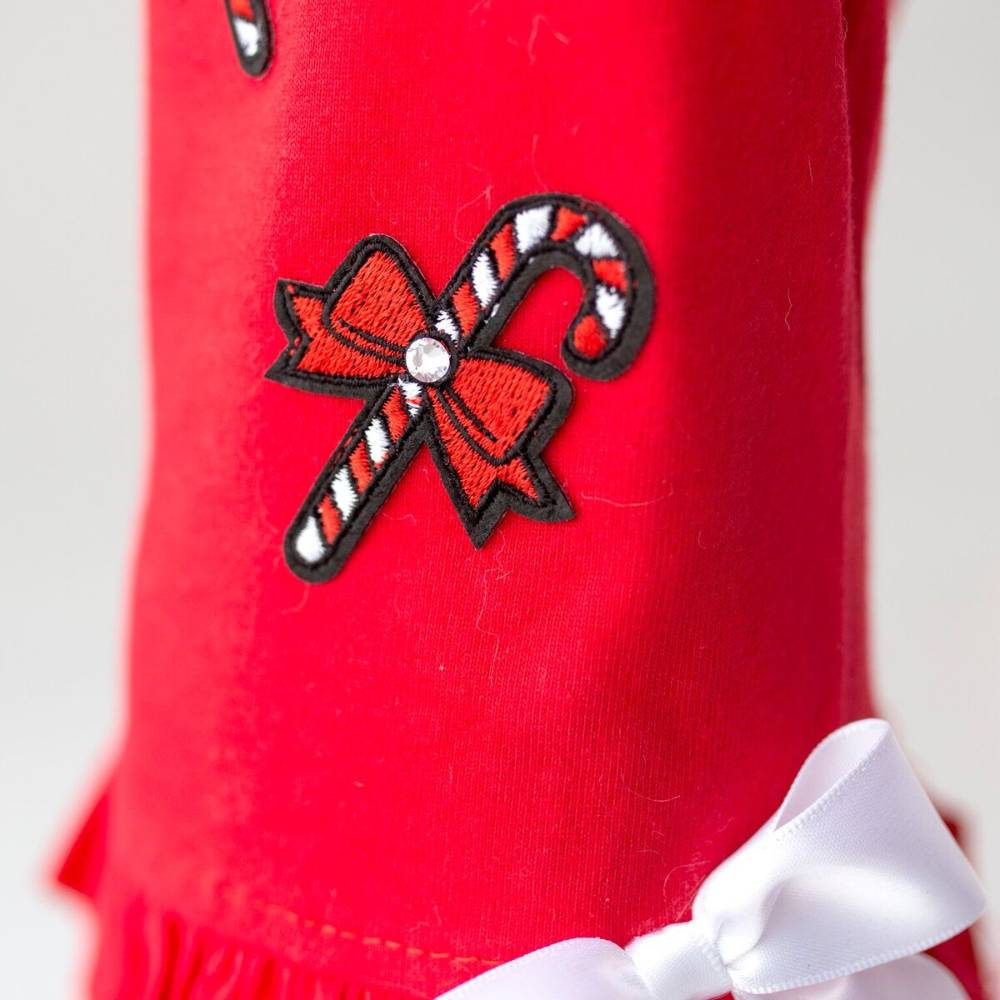 The image shows a close-up of a red Hello Doggie Candy Cane Dog Dress adorned with candy cane and bow embroidery, featuring a small rhinestone detail