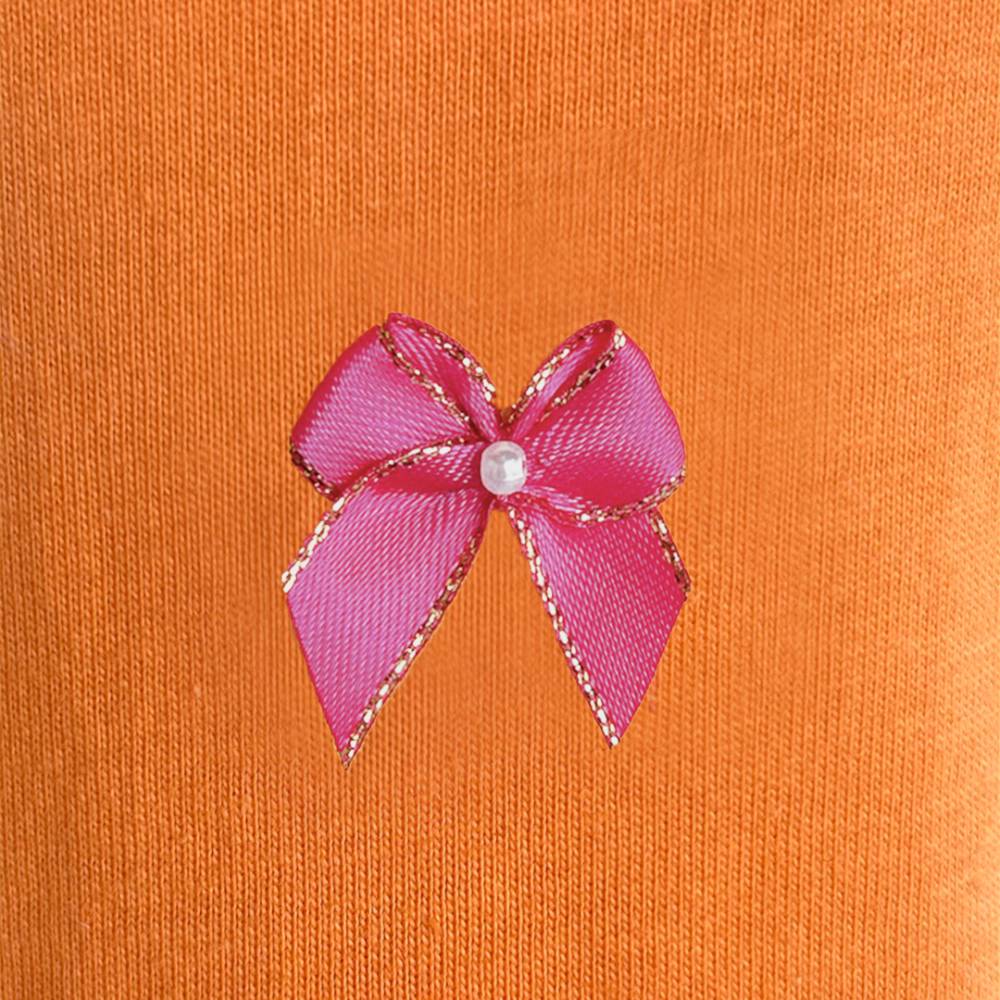 The image shows a detailed view of a pink bow with a pearl center on an orange background, part of the Hello Doggie Summer Dreams Dog Dress