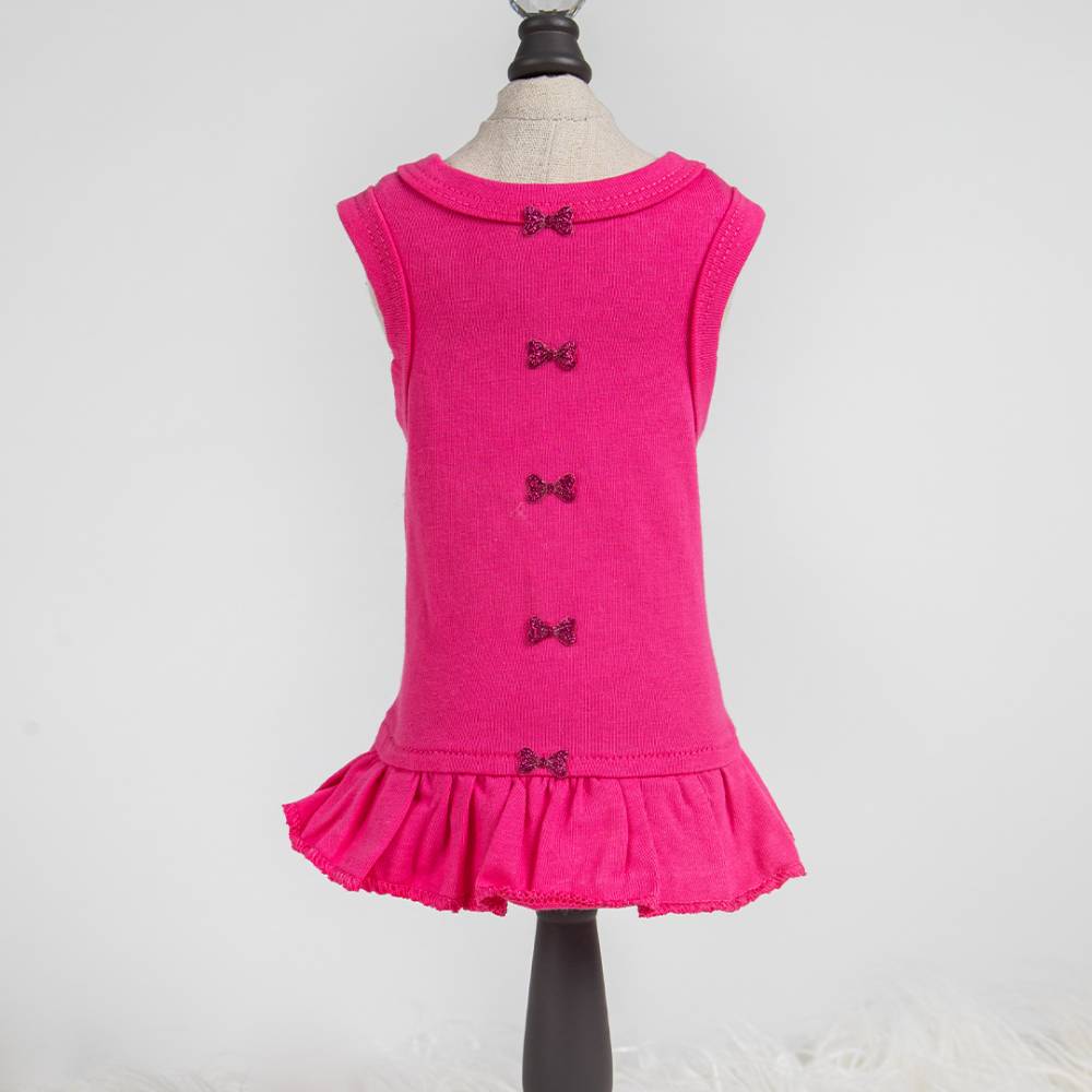 The image shows a fuchsia pink Hello Doggie Candy Dog Dress on a mannequin with small decorative bows down the back and a ruffled hem