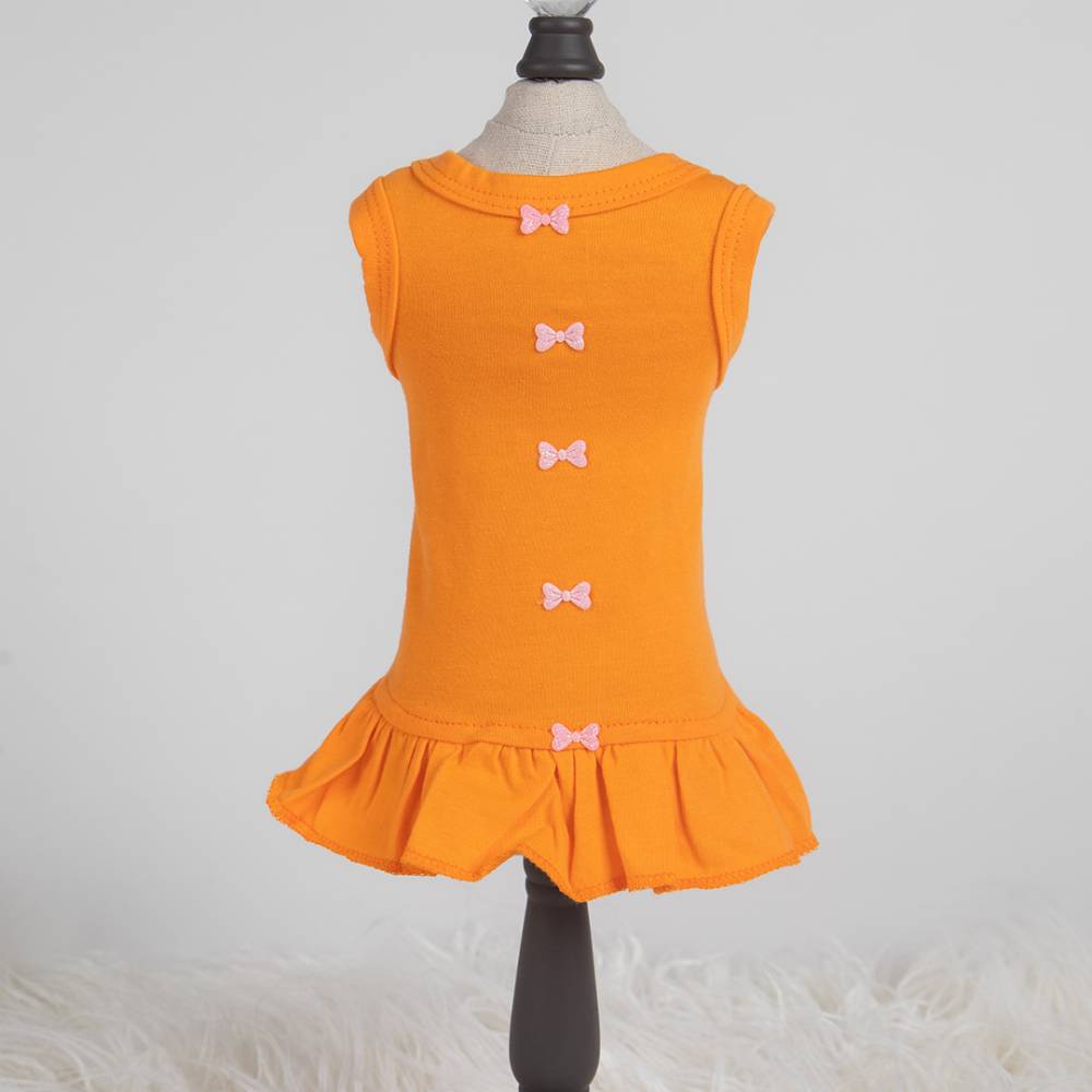 The image shows an orange Hello Doggie Candy Dog Dress on a mannequin with small decorative bows down the back and a ruffled hem