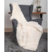 The image shows the cream-colored Hello Doggie Shag Throw Dog Blanket draped over a grey chair, highlighting its luxurious and fluffy design