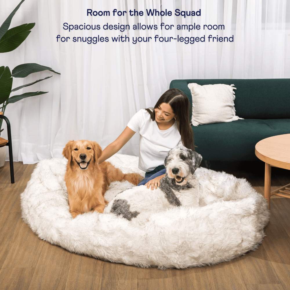 The spacious design of the White with Brown Accents Paw PupCloud™ Human-Size Faux Fur Memory Foam Dog Bed allows a woman and two dogs to comfortably snuggle together