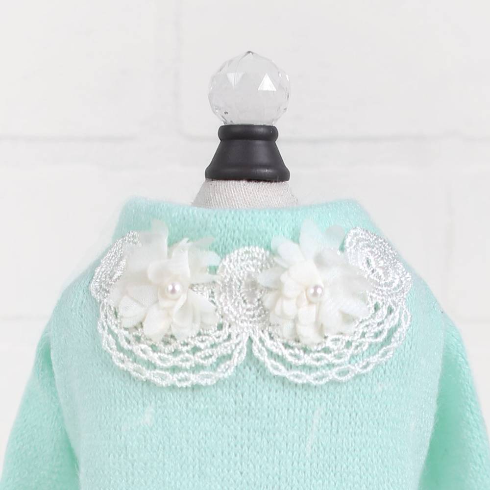 Th image shows a detailed view of the collar on the Hello Doggie Sweet Magnolia Dog Sweater in mint, with intricate lace and flower details