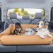 Two dogs are comfortably lying in the back seat of a car in the Paw PupProtector™ Faux Leather Memory Foam Dog Car Bed - Camel Portable Dog Bed